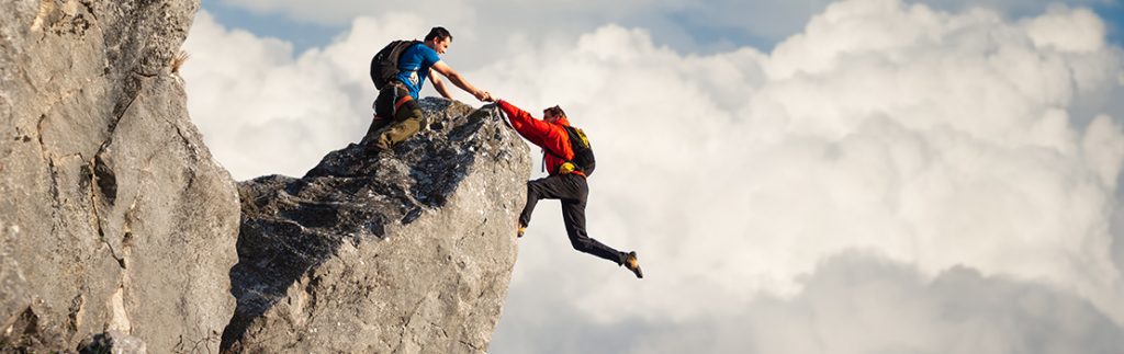 一个人帮助另一个人爬上一堵巨大的岩壁
