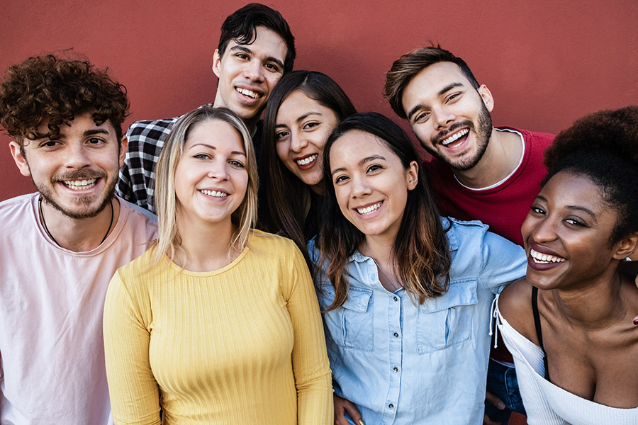 一群多种族青少年近距离站在一起 站在红色背景前他们笑起来似乎欢乐同龄同龄关系对青少年自杀率很重要,但积极的成人关系产生更大效果